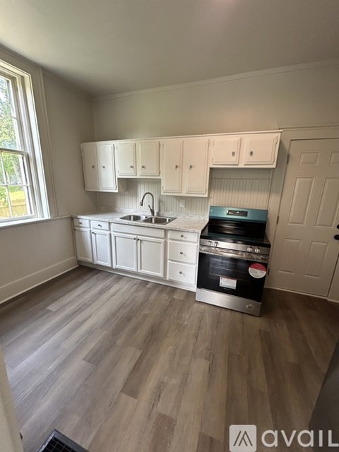 A kitchen with white cabinets and a wooden floor.