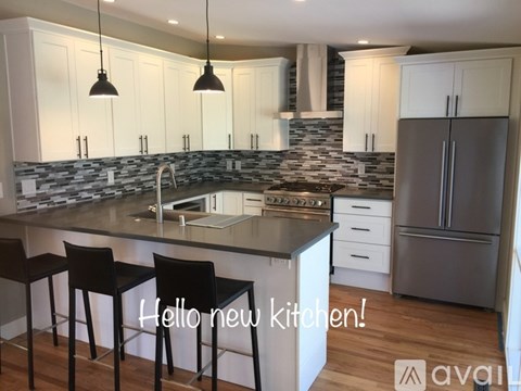 A modern kitchen with white cabinets and a stone backsplash.