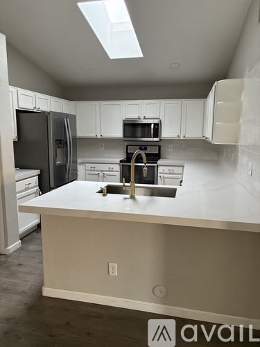 A kitchen with white cabinets and a white island with a sink.
