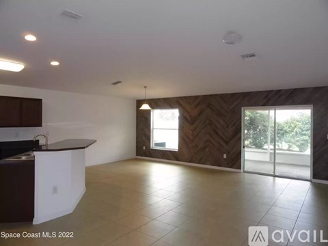 A spacious living room with a kitchen area and sliding glass doors.