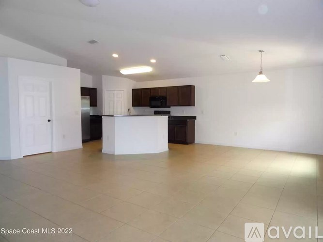 A spacious kitchen and living room with a white island in the middle.