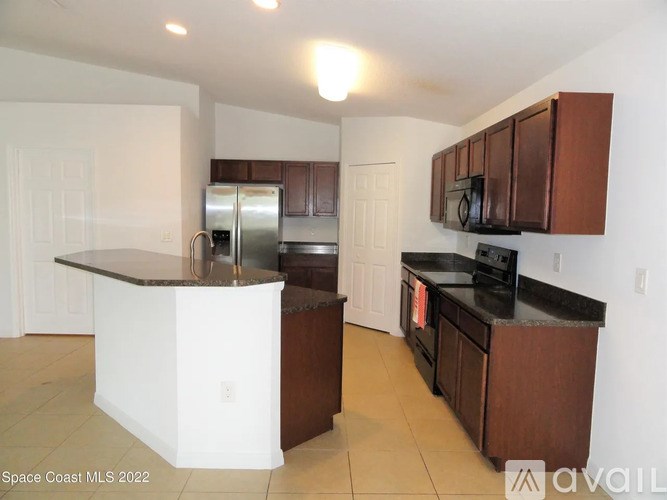 A kitchen with white walls and brown cabinets.