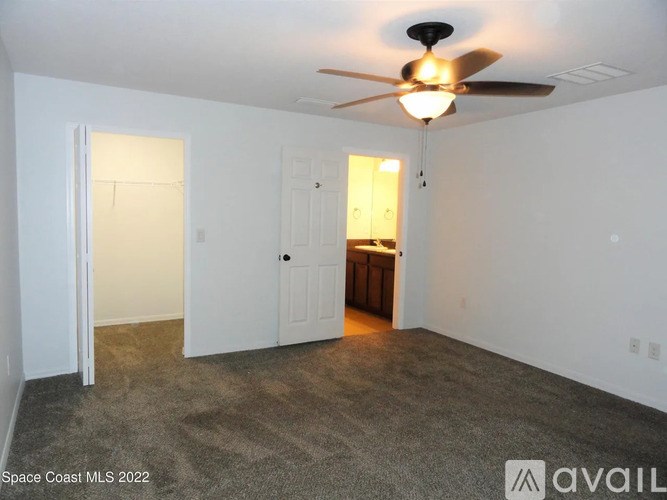 A room with a ceiling fan and carpeted floor.