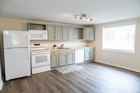 A kitchen with white appliances and wooden floors.