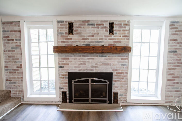A fireplace with a wooden mantle and a brick wall above it.