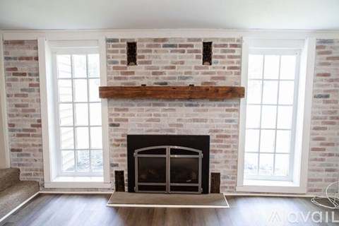 A fireplace with a wooden mantle and a brick wall above it.