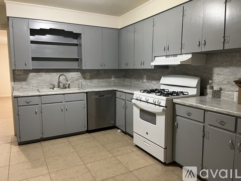 A kitchen with grey cabinets and a white stove top oven.