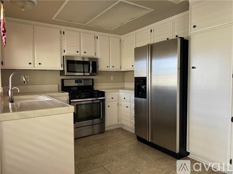 A kitchen with white cabinets and a stainless steel refrigerator.