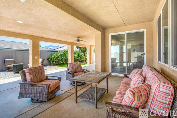 A patio with a striped couch, two chairs and a coffee table.