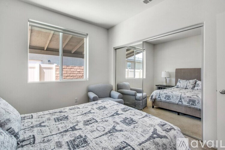 A bedroom with a bed, chair, and mirror.