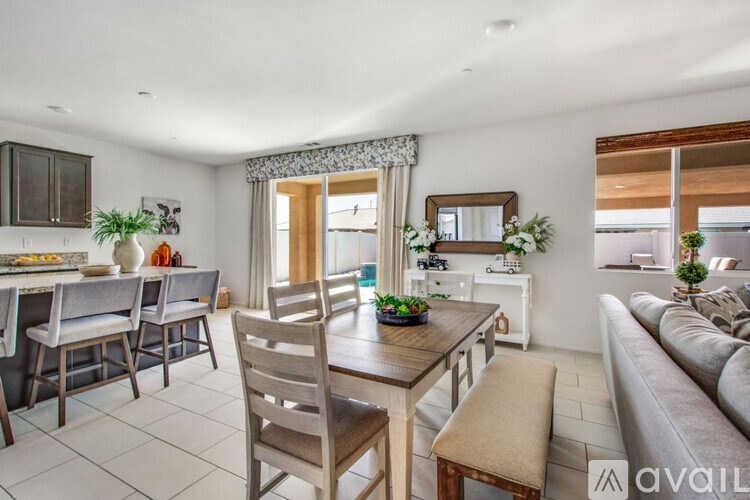 A well-lit, spacious living room with a dining area and a kitchen in the background.