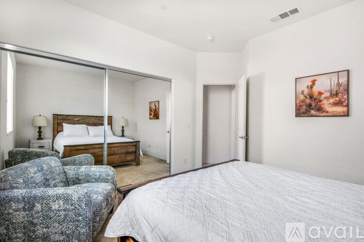 A bedroom with a large bed, a chair, and a painting on the wall.