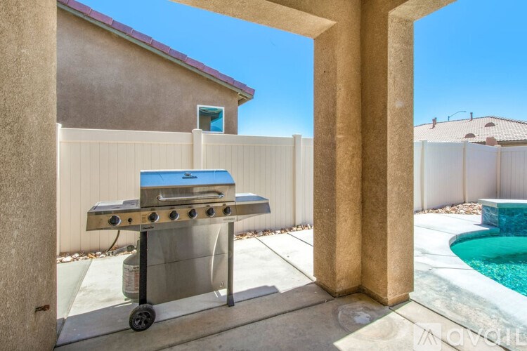 A barbecue grill is placed on a patio next to a pool.