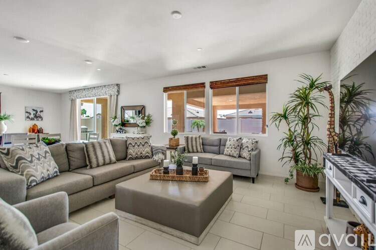 A living room with a grey sofa, a grey armchair, a coffee table, and a potted plant.