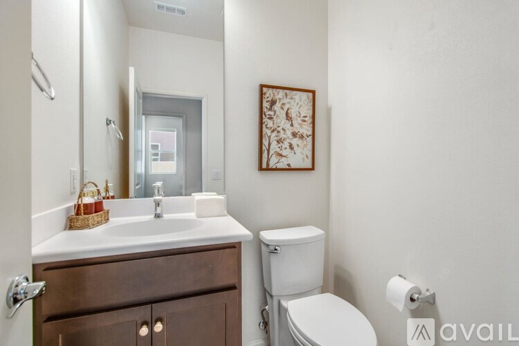 A bathroom with a toilet, sink, and mirror.