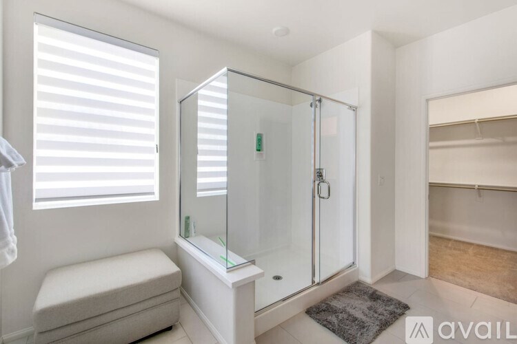 A bathroom with a glass shower enclosure and a bench seat.