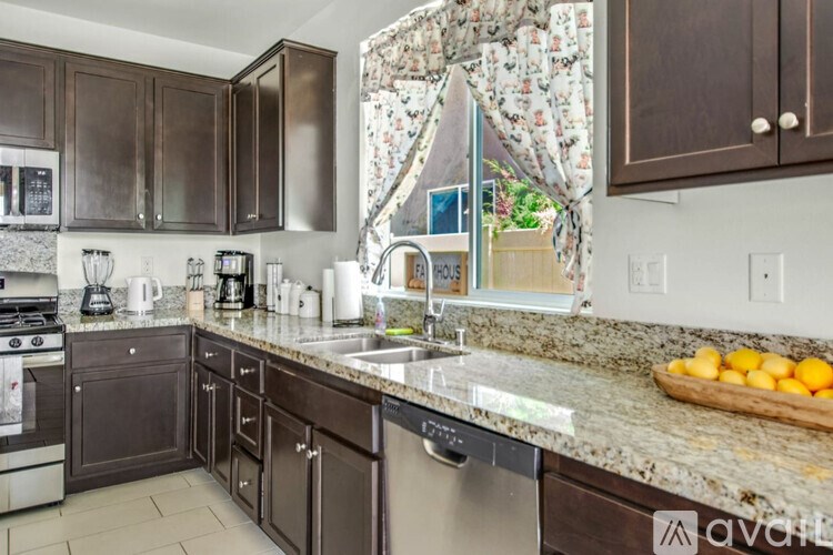 A kitchen with dark brown cabinets and granite countertops.