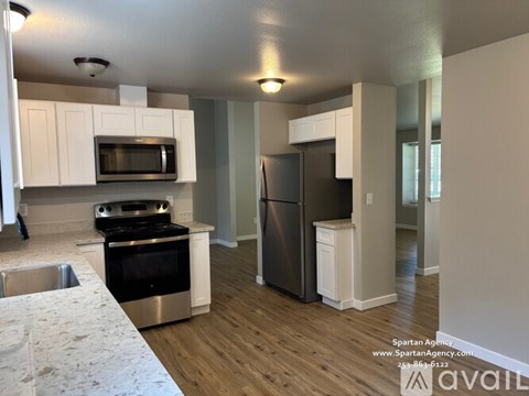 A kitchen with white cabinets and a stainless steel refrigerator.