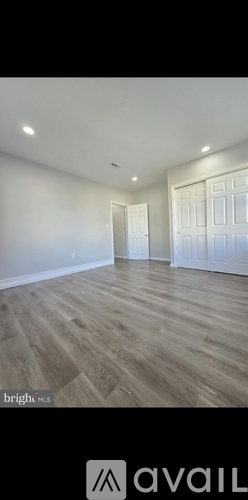A room with wooden flooring and white walls.