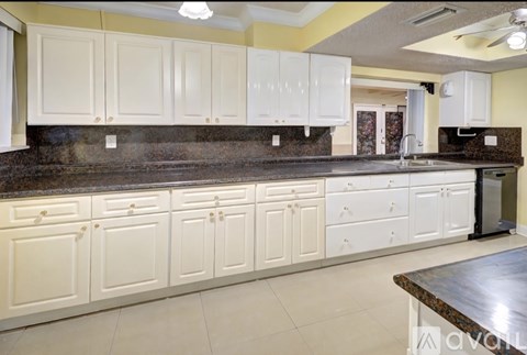 A kitchen with white cabinets and a dark counter top.