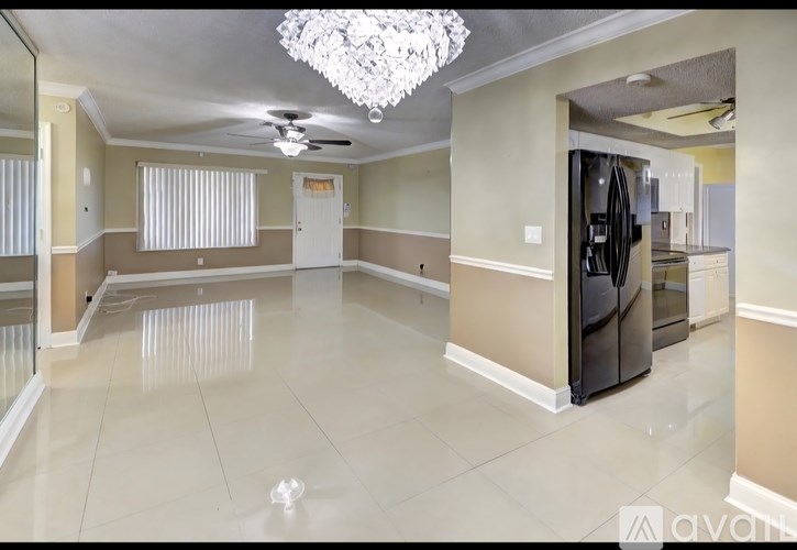 A spacious kitchen with a chandelier and a refrigerator.