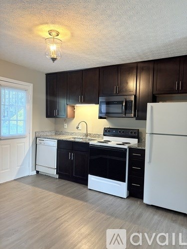 A kitchen with black cabinets and white appliances.