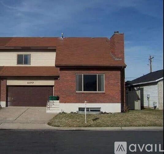 A two-story house with a garage and a brick chimney.