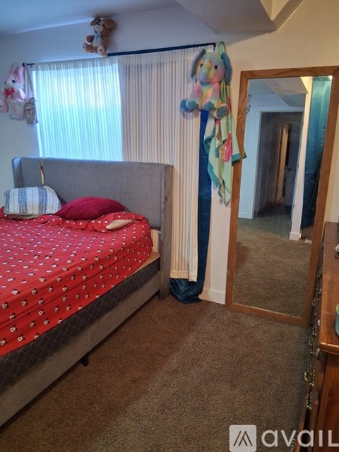 A bedroom with a red bedspread and a mirror on the wall.