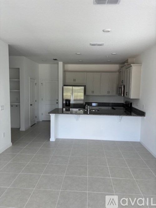 A kitchen with white cabinets and a black countertop.