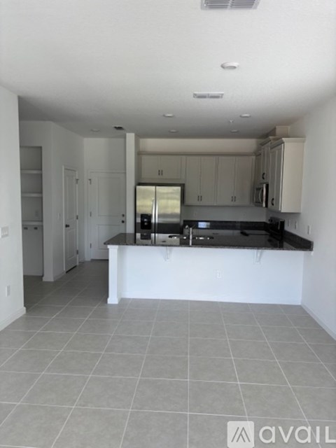 A kitchen with white cabinets and a black countertop.