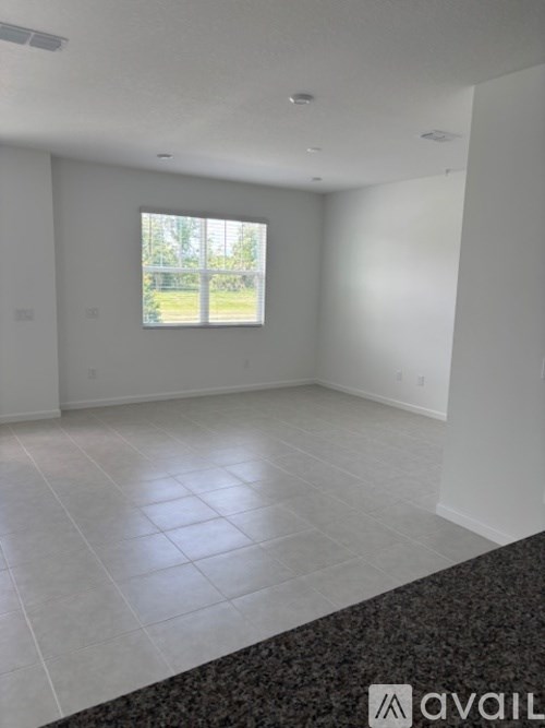A spacious room with a large window and tiled flooring.