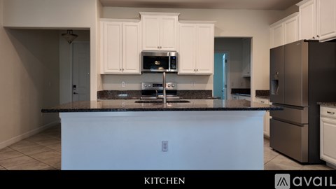 A kitchen with white cabinets and a black countertop.