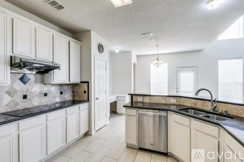 A kitchen with white cabinets and a black countertop.