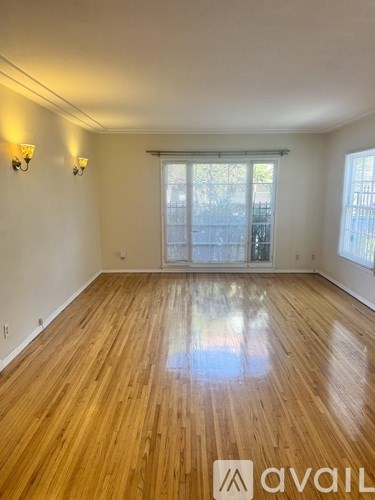 A room with wooden flooring and two wall sconces.