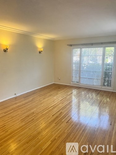 A room with wooden flooring and two wall sconces.