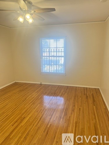 A room with wooden flooring and a window with blinds.