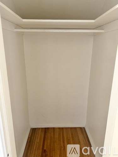 A small, empty room with wooden flooring and white walls.