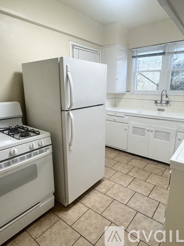 A kitchen with a white refrigerator, stove, and cabinets.