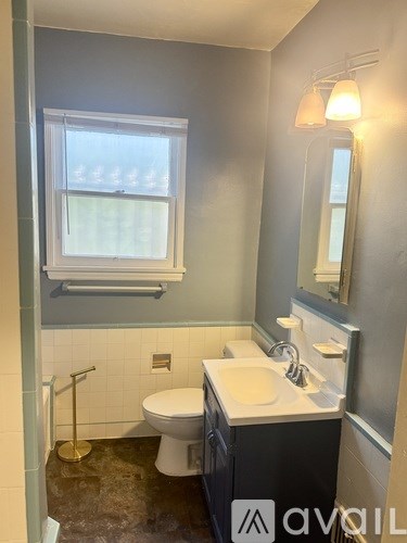 A bathroom with a toilet, sink, and mirror.