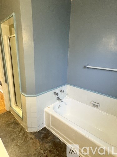 A bathroom with a white tub and a blue wall.