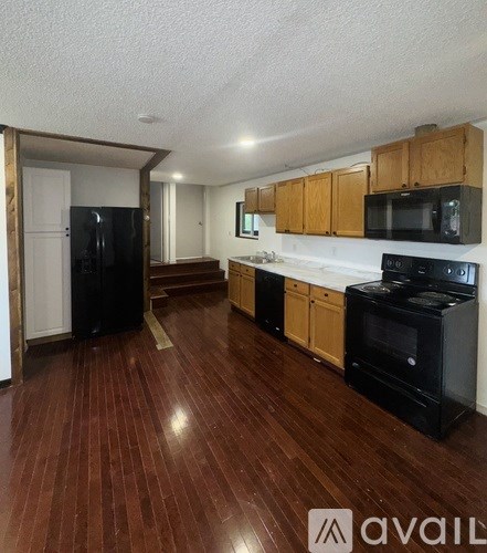 A kitchen with wooden floors and black appliances.