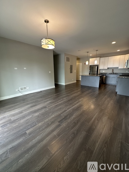 A spacious room with wooden flooring and a pendant light hanging from the ceiling.