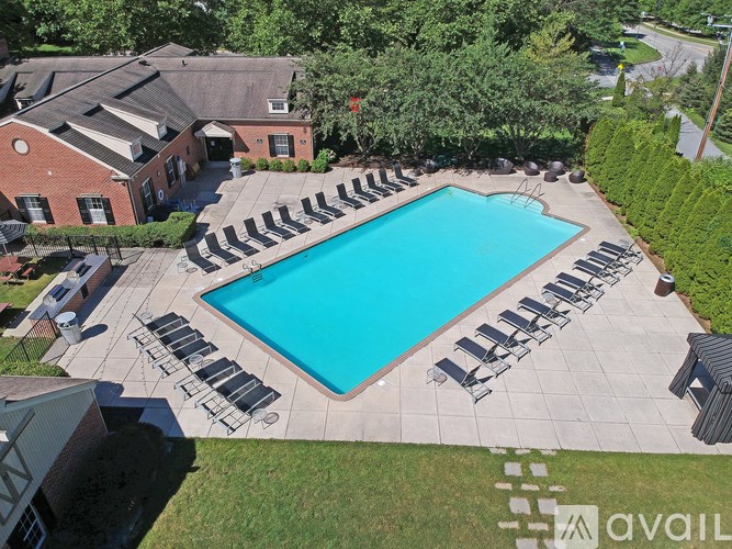 A pool surrounded by lounge chairs and trees.