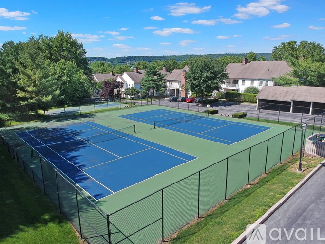 A tennis court surrounded by a green fence and trees.