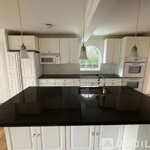 A kitchen with white cabinets and black countertops.