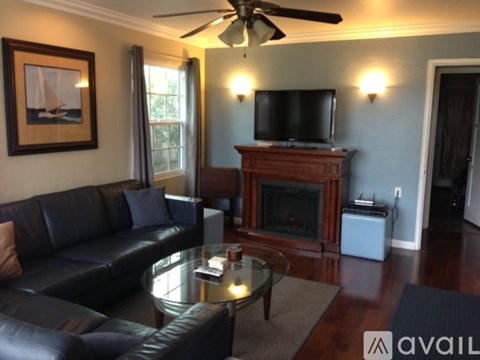 A living room with a black leather couch and a glass coffee table.