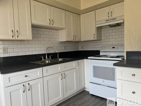 A kitchen with white cabinets and a black countertop.