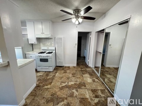 A kitchen with a white stove and a fan on the ceiling.