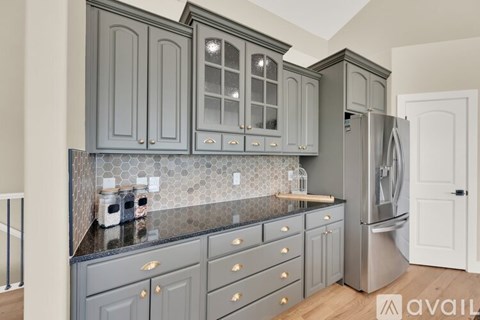 A kitchen with grey cabinets and a black countertop.