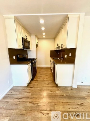 A kitchen with white cabinets and brown countertops.